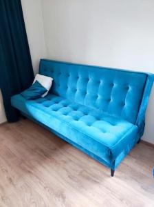 niebieska kanapa siedząca w pokoju z drewnianą podłogą w obiekcie Nikifour, apartament nad deptakiem w mieście Krynica Zdrój
