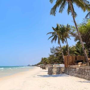 a sandy beach with palm trees and the ocean at Kanokkan Apartment in Hua Hin