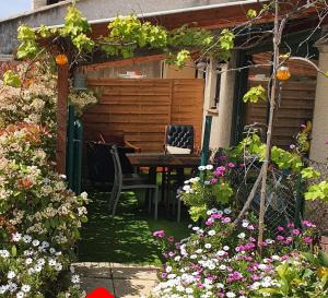 un jardín con mesa, sillas y flores en Cottage Perla Vita, en Le Cannet