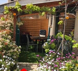 een tuin met een tafel, stoelen en bloemen bij Cottage Perla Vita in Le Cannet