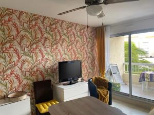 a living room with a tv and a table with chairs at Appartement GRUISSAN Plage du Grazel in Gruissan