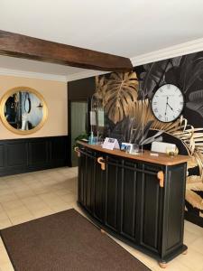 a room with a counter with a clock on the wall at Logis Domaine du Prieuré in Tonnay-Boutonne