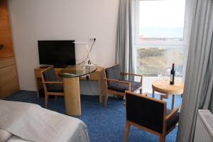 a room with a table and chairs and a television at Seafront Hotel in Hirtshals