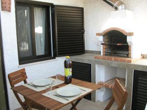 a wooden table with two chairs and a pizza oven at Almargem Villa 77 Cozy 1BR in Cabanas de Tavira, Near the Beach in Cabanas de Tavira