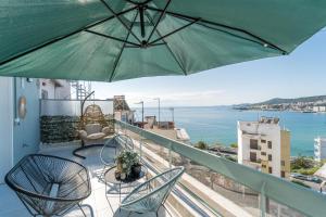 a balcony with chairs and an umbrella and the ocean at Aura Celestia in Kavála