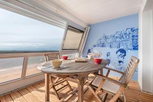 a table and chairs in a room with a view of the ocean at Face à la mer, appartement sous les toits pour 4 in Saint-Sébastien