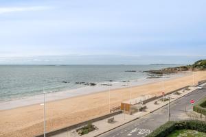 a view of a beach with a road and the ocean at Face à la mer, appartement sous les toits pour 4 in Saint-Sébastien