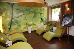 ポルチンズドロイにあるUzdrowisko Polczyn SPA Zaciszeの緑の椅子と木の絵が飾られたリビングルーム