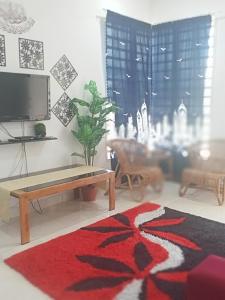 a living room with a table and a rug at Alif Homestay Changlun in Changlun