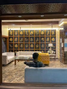 um homem sentado num sofá numa sala de estar em Hotel Sudarshan Palace em Lātūr