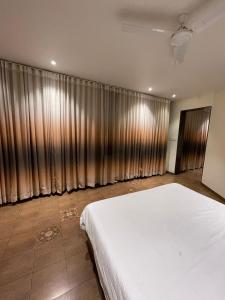 1 dormitorio con 1 cama blanca grande y cortinas en Hotel Sudarshan Palace, en Lātūr