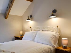 a bedroom with a white bed with two lamps at Troedyrhiw Isaf in Tregaron