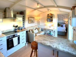 a kitchen with white cabinets and a living room at Sage - UK36937 in Lamerton