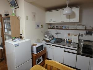 Una cocina con un refrigerador blanco y un microondas. en 京の宿 西大路 familie, en Kioto