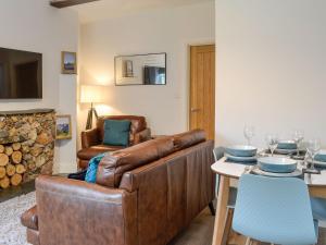 uma sala de estar com um sofá de couro e uma mesa em Howbeck Cottage em Hesket Newmarket