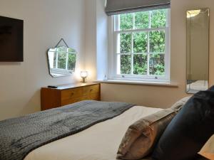 a bedroom with a bed and a window and a mirror at Howbeck Cottage in Hesket Newmarket