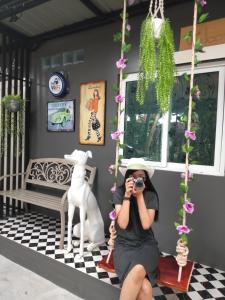 uma mulher sentada num baloiço a tirar uma fotografia a um cão em Ruenthip Homestay em Banguecoque