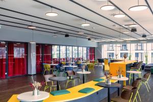 德累斯顿MEININGER Hotel Dresden Zentrum的一间设有桌椅和窗户的自助餐厅