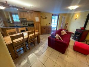 a living room with a red couch and a kitchen at Bilocale pietra e legno immerso nella natura in Morgex