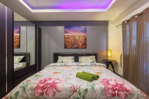 a bedroom with a large bed with pink flowers on it at Kanokkan Apartment in Hua Hin