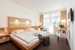 Habitación de hotel con cama grande y escritorio. en Park-Hotel am Rhein - Gesundheitshotel und Residenzen, en Rheinfelden
