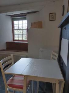 a table and chairs in a kitchen with a refrigerator at Longhouse - Hen Dy in Rhayader