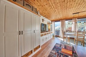 a kitchen with white cabinets and a dining room with a table at Appartement Kogelblick in Saalbach Hinterglemm