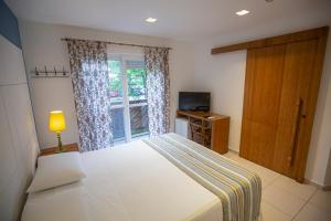 a bedroom with a bed and a window and a door at Juquehy Praia Hotel in Juquei