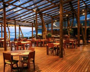 a restaurant with tables and chairs and the ocean at Juquehy Praia Hotel in Juquei