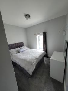 a white bedroom with a bed and a window at Station House Apartment Portstewart in Derry Londonderry