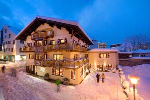 a group of people standing outside of a building in the snow at Hotel Glasererhaus in Zell am See