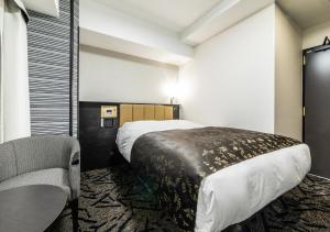 a hotel room with a bed and a chair at APA Hotel Kobe Sannomiya Ekimae in Kobe