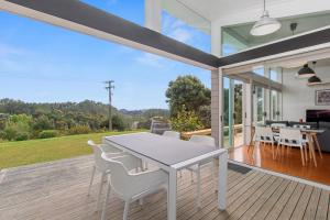 une salle à manger avec une table blanche et des chaises sur une terrasse dans l'établissement Paroa Bay Chalets - Te Whare Kereru, à Russell