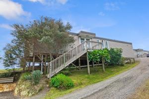 a house with a staircase in front of it at Paroa Bay Chalets - Te Whare Tui in Russell