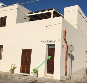un edificio blanco con una flecha verde. en Casa Emma en Favignana