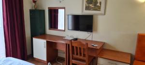 a bedroom with a desk with a television on a wall at Hotel SYM in Ploieşti