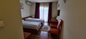 una piccola camera con due letti e una finestra di Hotel SYM a Ploieşti