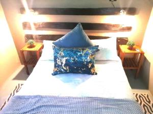 a bed with a blue pillow on top of it at Cango Retreat Quiet in Oudtshoorn