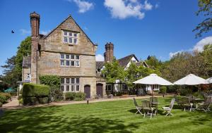 a house with lawn chairs and umbrellas in front of it at Ockenden Manor Hotel & Spa in Cuckfield