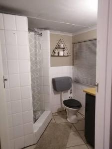 a bathroom with a black toilet and a shower at Cango Retreat Quiet in Oudtshoorn