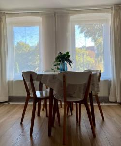 een eettafel met 2 stoelen en een vaas met bloemen bij Brezno Apartament in Gdańsk