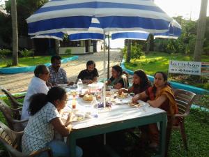 a group of people sitting at a table under an umbrella at La Mirban in Varkala