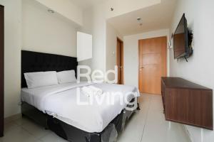 1 dormitorio con 1 cama y TV en la pared en RedLiving Apartemen Evenciio - WIN Property Tower 1, en Depok