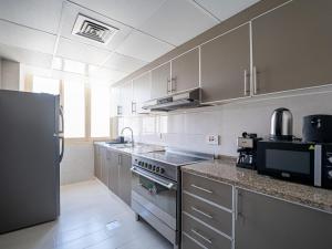 a kitchen with stainless steel appliances and a refrigerator at Soft touch & Spacious 2 Bed next to Metro in Dubai