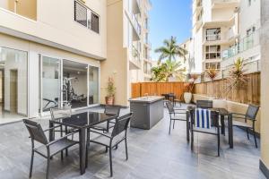 a patio with tables and chairs on a balcony at Redvue Holiday Apartments in Redcliffe