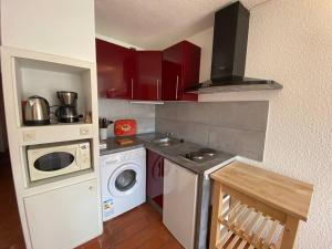 een kleine keuken met rode kasten en een wasmachine bij Studio Port Barcarès, 1 pièce, 4 personnes - FR-1-81-447 in Le Barcarès