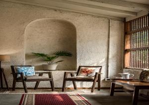 a room with two chairs and a table and a window at SaffronStays Amolee, Alibaug in Alibaug