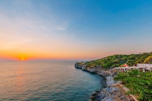 a sunset over the ocean with a resort on a cliff at Somewhere Koh Sichang in Ko Si Chang