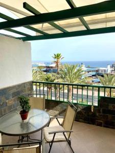 un patio con tavolo, sedie e vista sull'oceano di Apartamento vista mar en Flamboyan - San Agustín a San Bartolomé