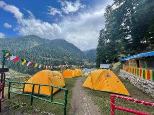 a group of tents parked in a field with mountains at Cafe Him, Tosh in Kalgha